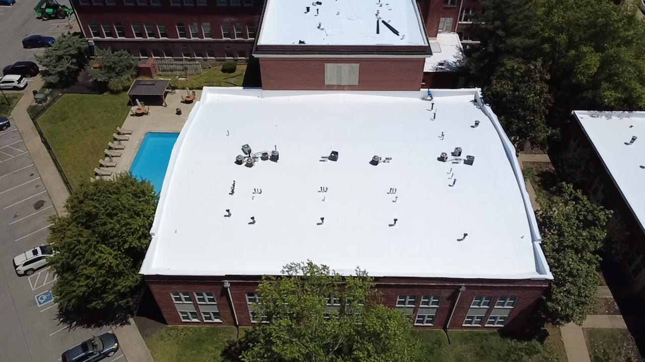 Aerial view of a completed white TPO roof on a large brick building